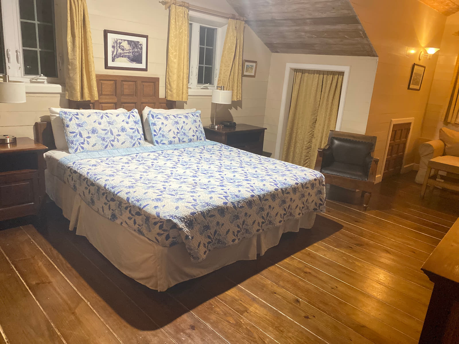 The Penthouse Suite's bedroom, a king bed on wide plank floors beneath a sloped white ceiling