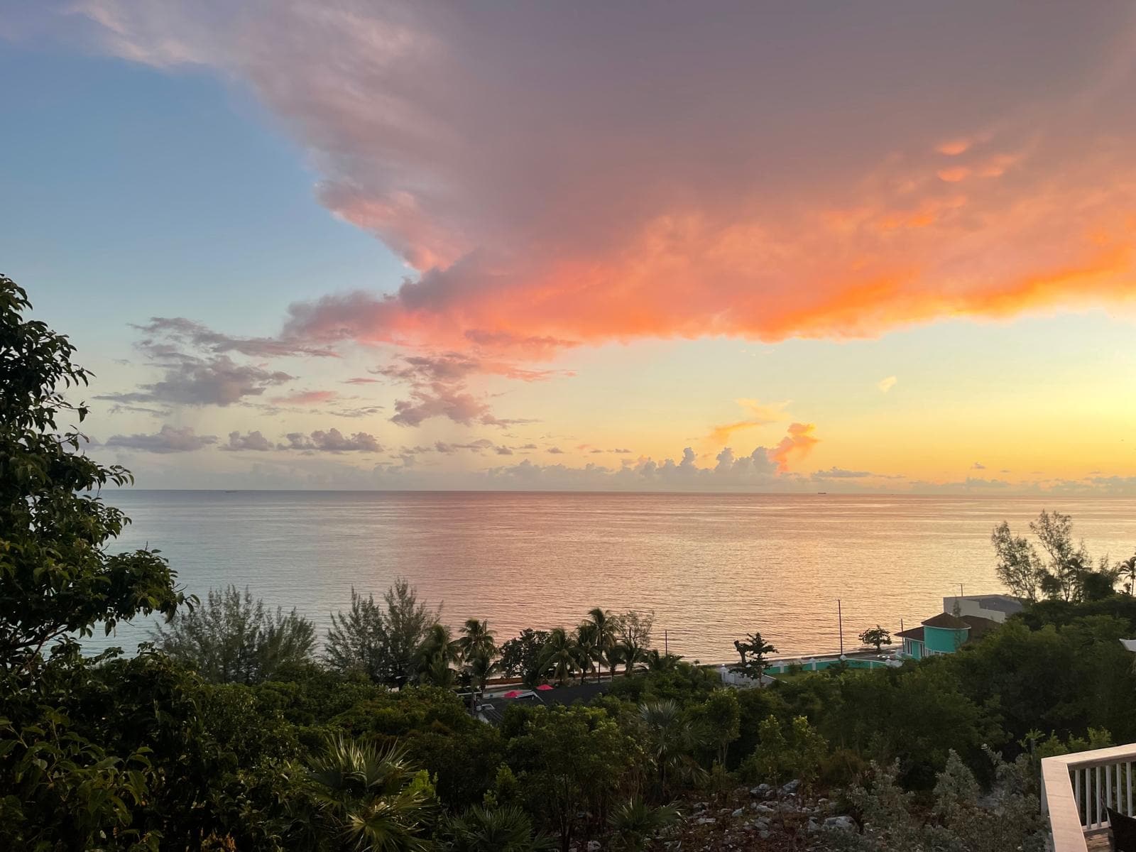 Sunset over the water from the hilltop, cloud banks lit orange and pink above a silvered sea